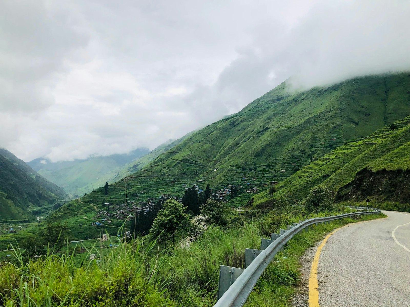 Mountain road curving past green terraced hillsides
